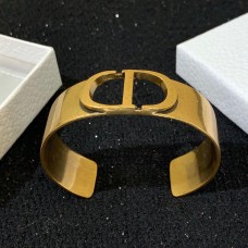 Náramek Christian Dior 30 Montaigne s motivem CD v antickém zlatém provedení s dutým přívěskem a mosaznou manžetou.